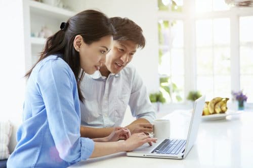 Asian Couple Looking at Laptop In Kitchen