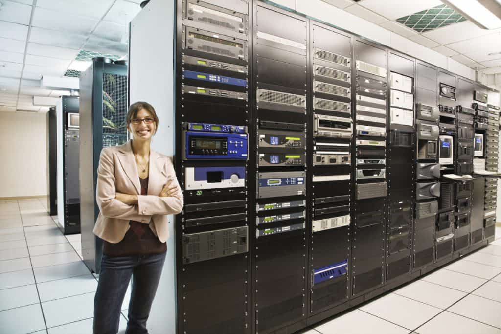 Portrait of female technician working in a large computer server room.